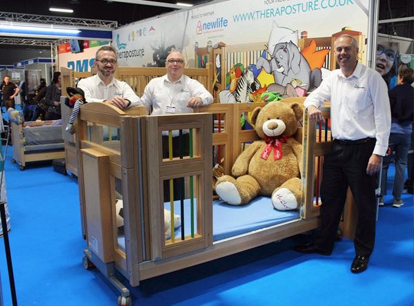 Salesmen stood around a cot with teddy bear